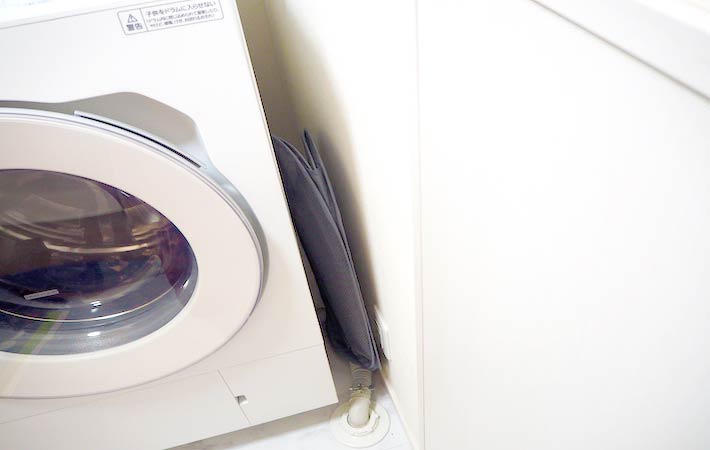 『ホッピングバッグカラーＬ ３４×３２×５７ｃｍ』くるっと入れ込むように折り畳み、洗濯機横の狭いスペースに収納した様子