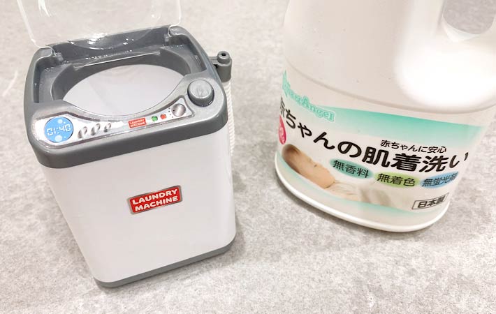 『ミニ洗濯機（電池式）』と洗濯に使用する『赤ちゃんの肌着洗い用洗剤』を並べた様子