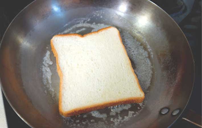 バターをひいたフライパンで食パンを焼いている写真