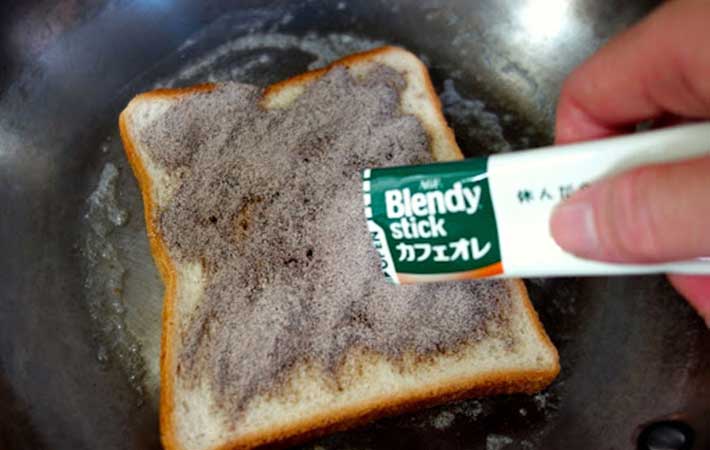 フライパンで焼いている食パンに『「ブレンディ®」スティック カフェオレ』をまぶしている写真