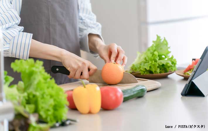 キッチンで野菜を切る写真