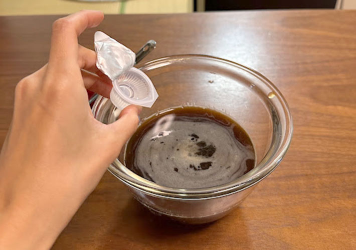 水に溶かしたコーヒーにガムシロップを入れる写真