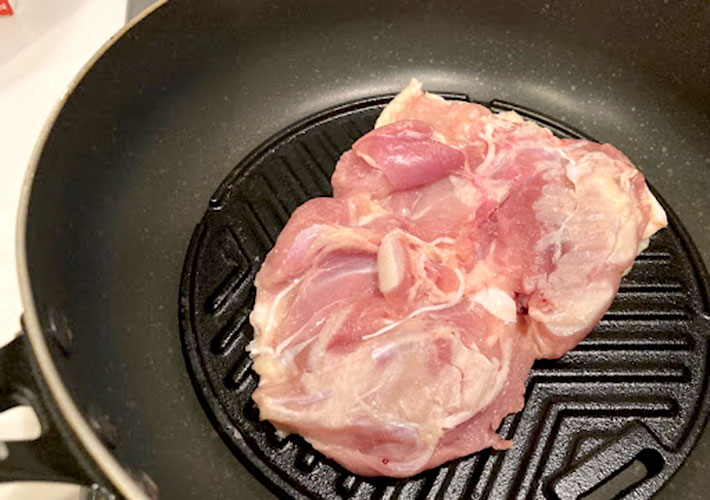 ニトリの『グリルプレート』をフライパンの上で鶏モモ肉を焼いている写真