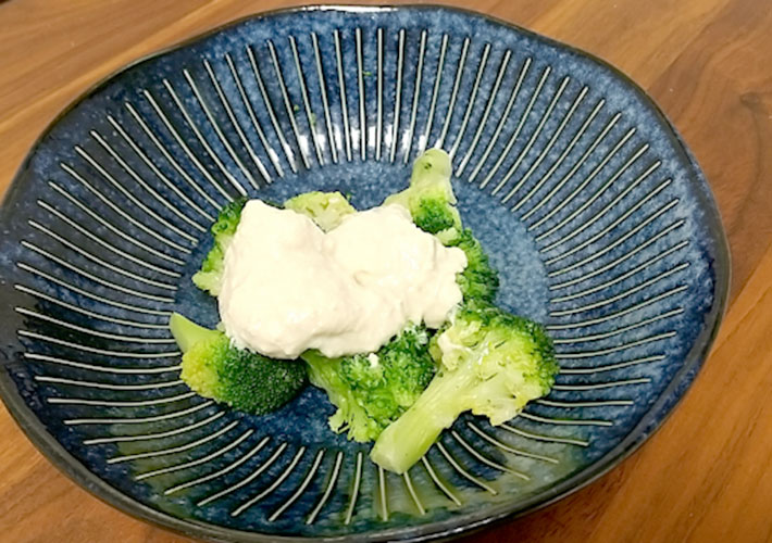 豆腐で作ったマヨネーズを皿に盛り付けたブロッコリーにかけた写真