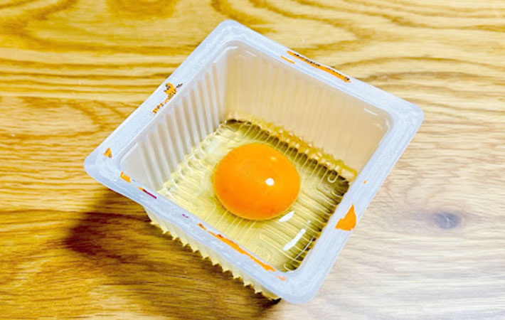 凸凹が付いた豆腐の空き容器に入れた卵の写真