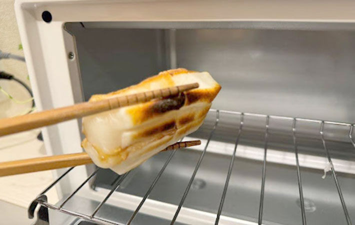 焼きあがった醤油を垂らした切り餅をオーブントースターから取り出した写真