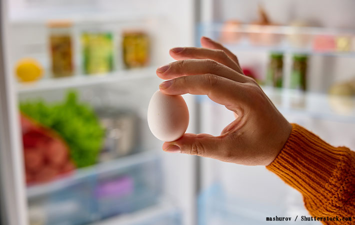 冷蔵庫から白い鶏卵を取る写真