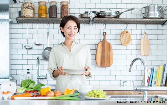 キッチンで食器を持つ女性の写真