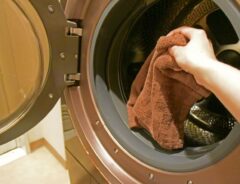 洗濯機に入ったブラウンのタオルをつかむ手