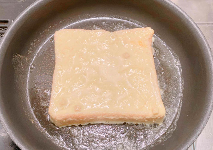 バターを塗ったフライパンでフレンチトーストを焼いているところの写真