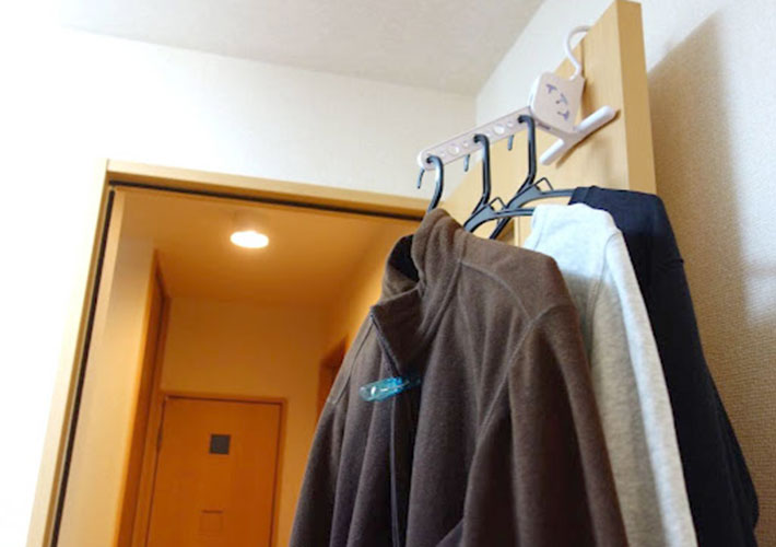 部屋のドアに『室内干しハンガー（５連 角度調整可）』を設置して服を干している写真