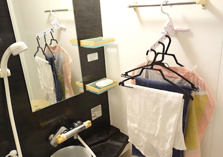 風呂場のタオル掛けに『室内干しハンガー（５連 角度調整可）』を引っ掛けて服を干している写真
