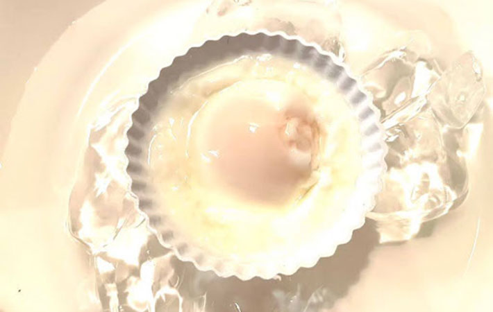 茹であがったカップに入った卵を氷水で冷やしている写真