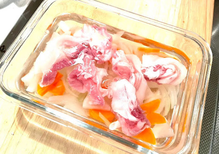 レンジで加熱したカット野菜に水と豚肉に入れた写真