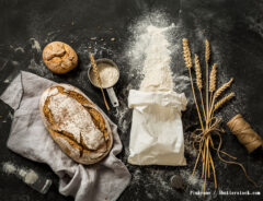 白い紙の袋から小麦粉がこぼれ計量カップとパンの写真