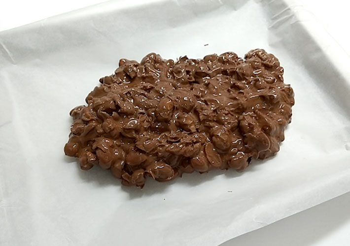 混ぜ合わせた福豆とチョコレートをクッキングシートの上に流しいれた写真