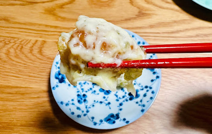 焼きおにぎりの天ぷらチーズのせを箸で手に取った写真