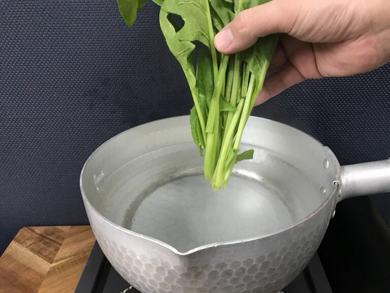 鍋に葉物野菜を入れようとしている様子