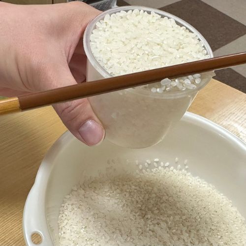 カップですくった米を箸でならしている様子
