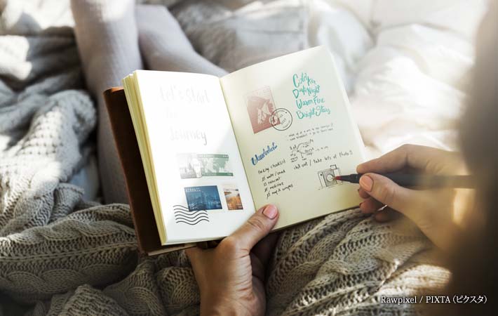 ベッドで日記を書く女性の写真