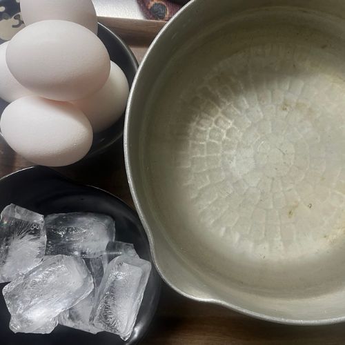 テーブルの上に並べられた卵、鍋、氷