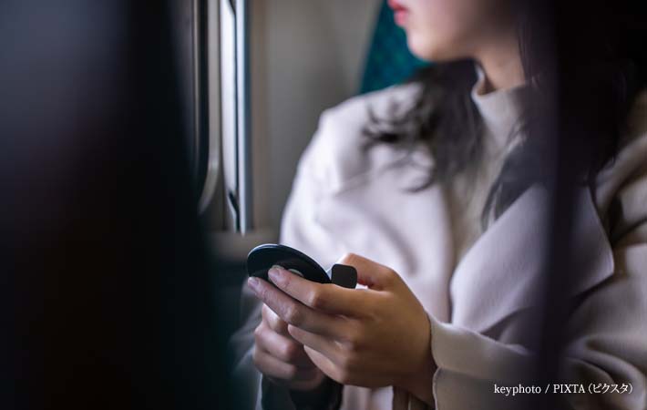 電車でメイク直しをする女性の写真