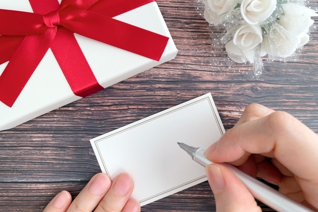 プレゼントとメッセージカードを書く手元の画像