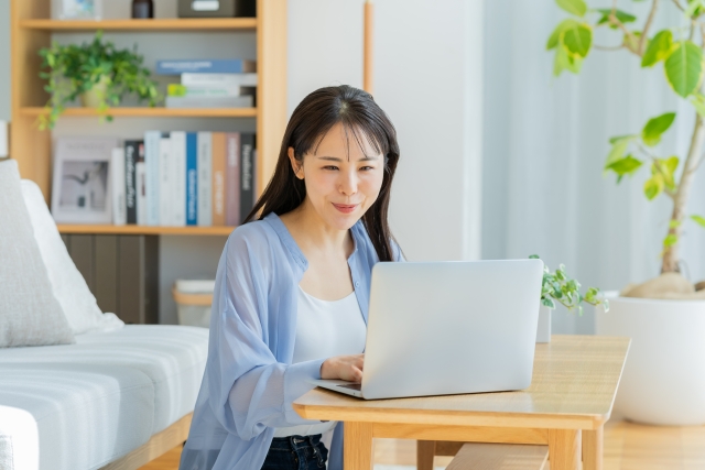 自宅でノートパソコンを操作する若い女性の画像