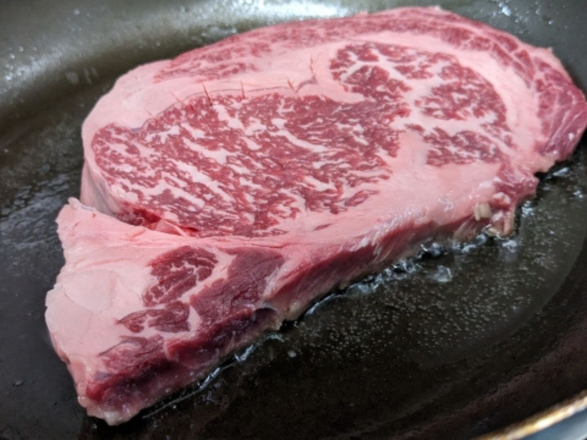 フライパンで焼かれているステーキ肉