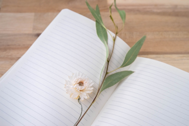 ノートと白い花の画像