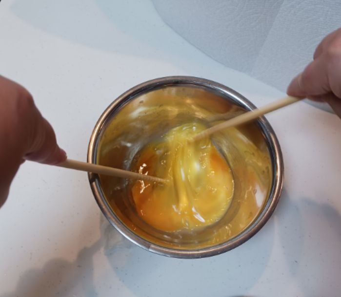 ボウルに入れた卵を菜箸で切るように混ぜる様子