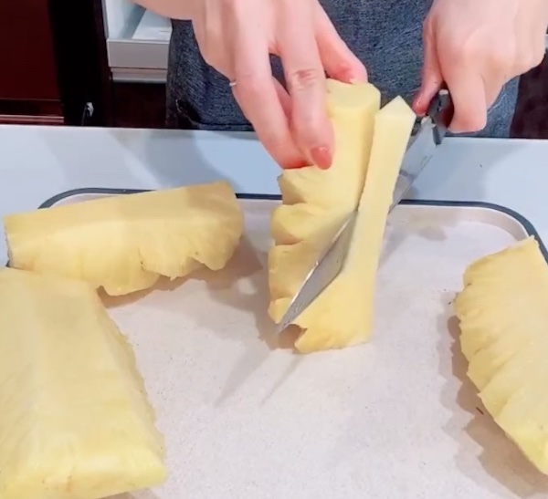 パイナップルの芯を包丁で切り落とす様子