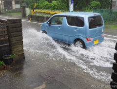 冠水した道路を走る車の写真