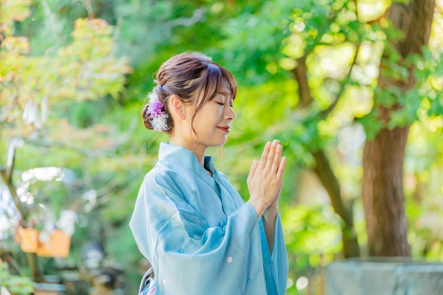 神社で参拝をする浴衣姿の女性の画像