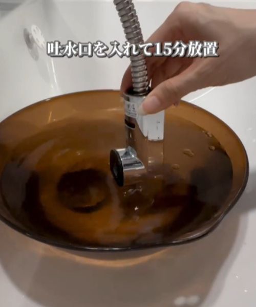 クエン酸を溶かしたお湯を入れた洗面器に吐水口を入れる様子