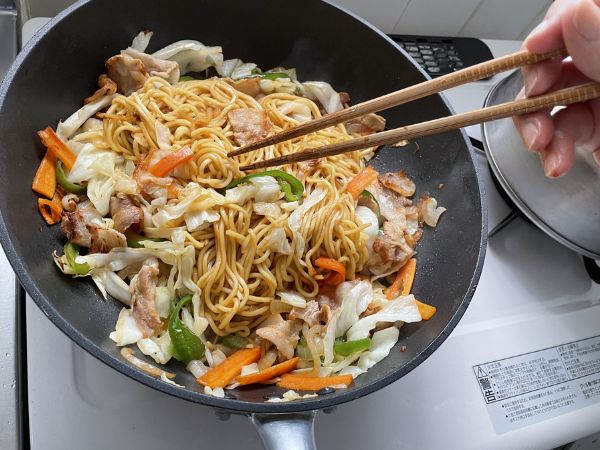 フライパンで焼きそばを炒める様子