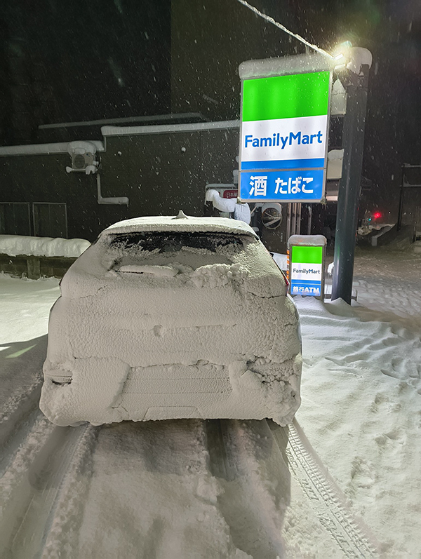 雪が積もったコンビニの駐車場の写真