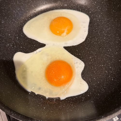 2つの目玉焼きをフライパンで焼く様子