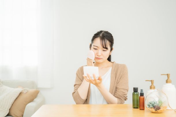 困った顔をしながらファンデーションを塗る女性の写真