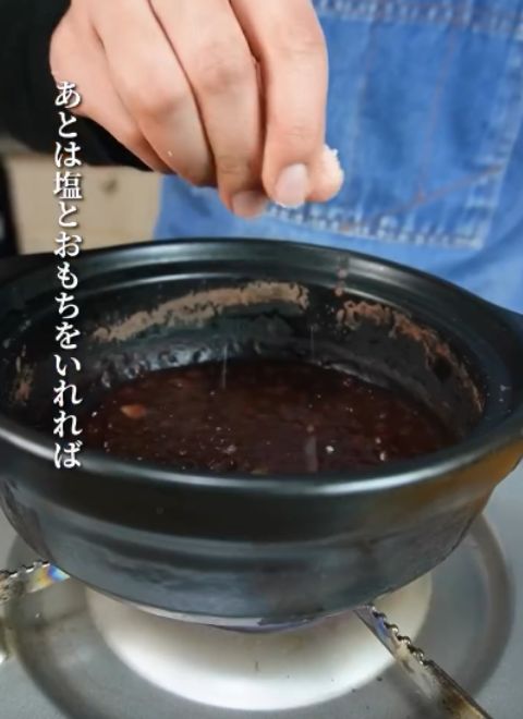 小豆を煮込んだ鍋に塩をひとつまみ入れる様子