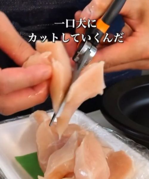 キッチンばさみで鶏胸肉をカットする様子