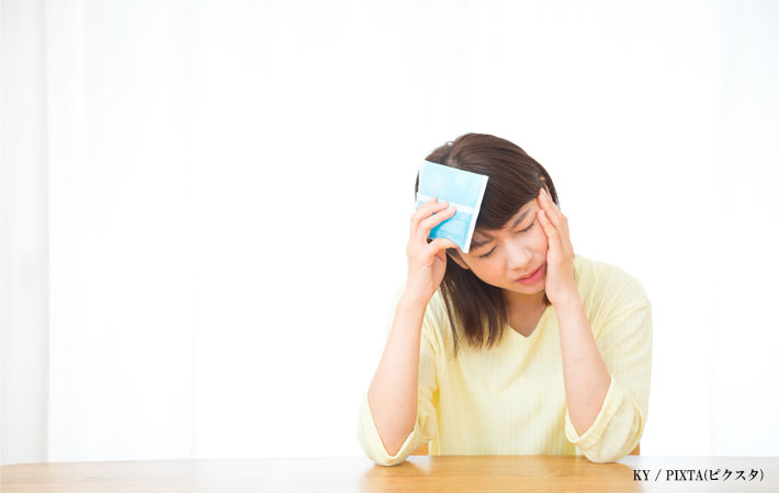 頭に保冷剤をあてる女性の画像