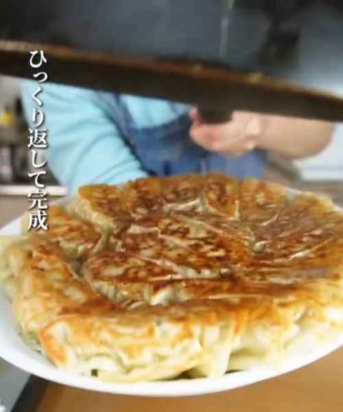 焼きあがった餃子をフライパンからひっくり返して皿に取り出した様子