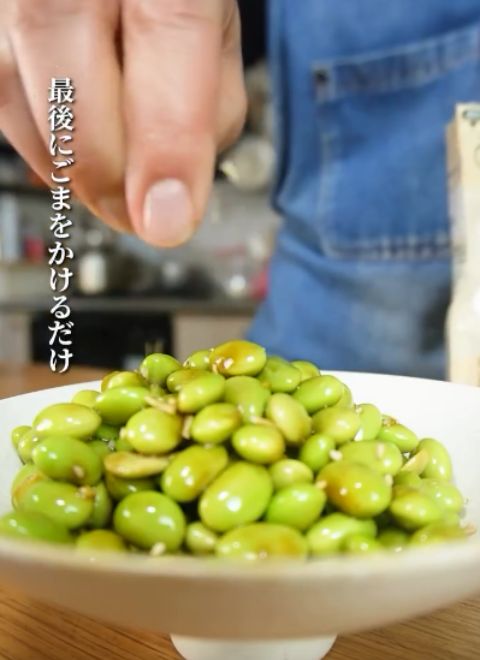 調味料と合わせた枝豆を皿に盛ってごまをかける様子