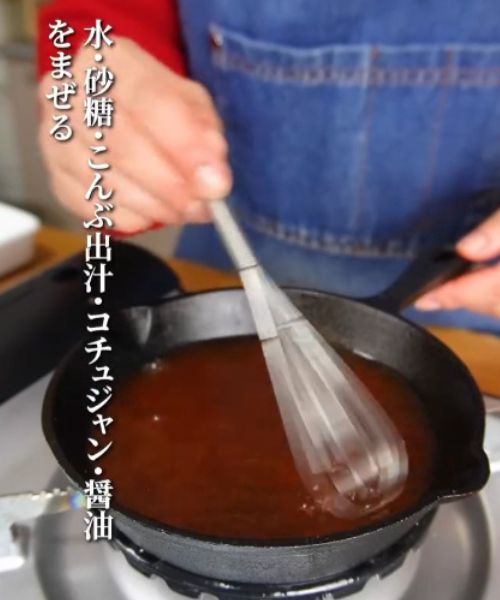 フライパンに入れた調味料を泡立て器で混ぜる様子