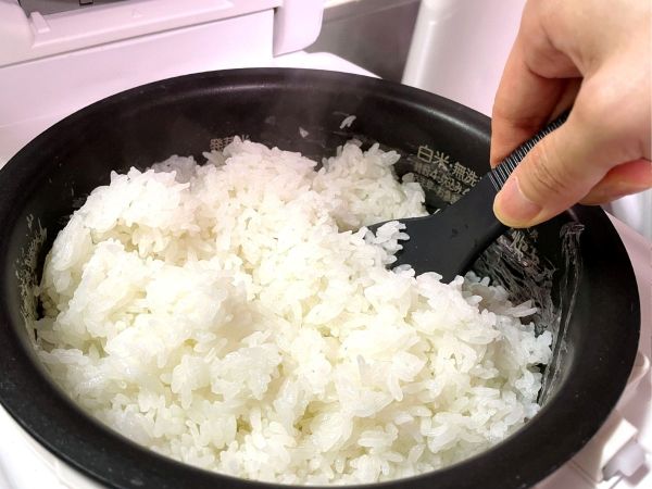 炊飯釜に炊けたご飯にしゃもじを入れる様子