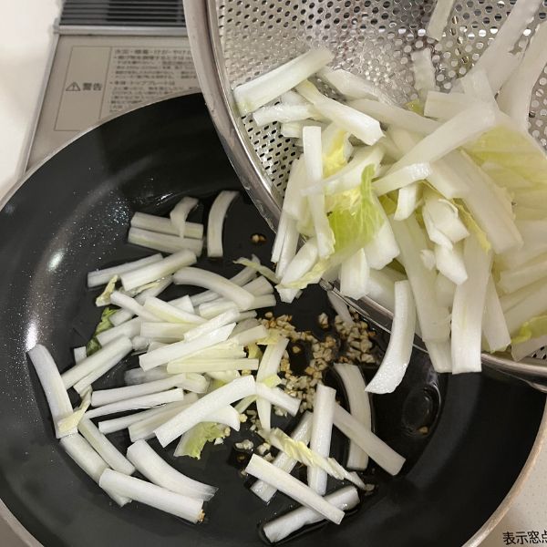 千切りにした白菜をフライパンに入れる様子