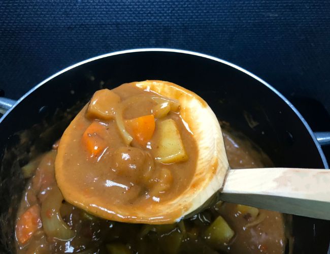 鍋に作ったカレーをお玉ですくい上げた様子