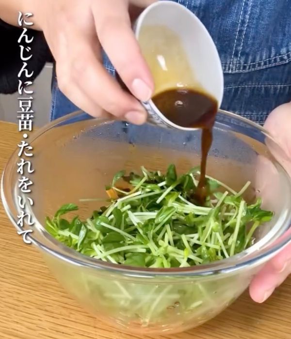 豆苗とニンジンの入ったボウルに混ぜ合わせた調味料を回しいれる様子