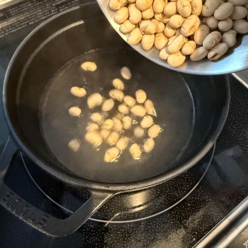 鍋に沸かしたお湯の中に節分豆を入れる様子